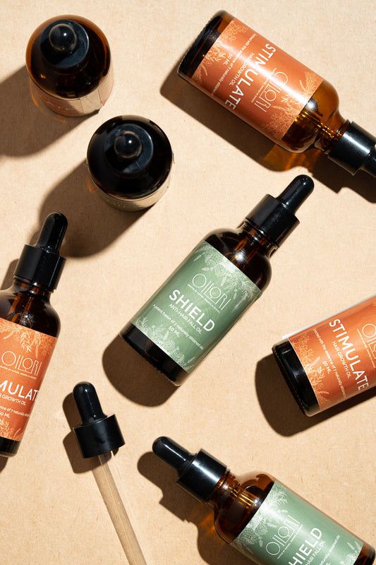 Collection of  haircare bottles with visible labels on a beige background with botanical ingredients names